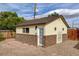 Rear view of a home with a tan exterior and brick base, minimal landscaping and small patio at 1017 E Oakey Blvd, Las Vegas, NV 89104