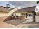 View of gated carport and tan exterior with brick base, dark roof, and minimal landscaping at 1017 E Oakey Blvd, Las Vegas, NV 89104
