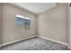 This bedroom features neutral-colored walls, carpet flooring, a window for natural light, and minimalist design at 2194 Pigeon Hawk St, Las Vegas, NV 89138