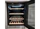 Close up of a stylish built-in wine fridge with wood shelving at 2194 Pigeon Hawk St, Las Vegas, NV 89138