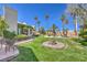 Spacious backyard with lush green grass, palm trees, covered patio, and a cozy fire pit area at 2201 Country Cottage Ct, Las Vegas, NV 89117