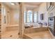 Bright bathroom features a glass shower and a relaxing tub under arched windows at 2201 Country Cottage Ct, Las Vegas, NV 89117