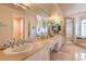 The opulent bathroom features dual sinks, a large mirror, and tiled shower and tub at 2201 Country Cottage Ct, Las Vegas, NV 89117
