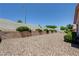 Desert-scaped backyard features a stacked rock retaining wall, mature bushes, and clear blue skies at 2545 Banora Point Dr, Las Vegas, NV 89134
