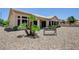 Back exterior showcases the house, covered patio, desert landscaping, mature palms, and a bench at 2545 Banora Point Dr, Las Vegas, NV 89134