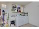 Functional laundry room includes washer, dryer, utility sink, and shelving for storage of cleaning supplies at 2545 Banora Point Dr, Las Vegas, NV 89134