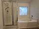 Bathroom features a shower and a soaking tub with tiled surround and a view to the neighborhood at 6638 Babys Tear Pl, Las Vegas, NV 89148