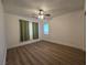 Inviting bedroom with wood-look floors, a ceiling fan, and green accent curtains at 6638 Babys Tear Pl, Las Vegas, NV 89148