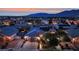 Aerial view of a residential neighborhood showcasing homes, landscaping, and mountain views at dusk at 7300 Fresh Harvest Ave, Las Vegas, NV 89131