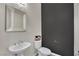 Modern powder room with stylish mirror, pedestal sink, and a sophisticated dark accent wall at 7300 Fresh Harvest Ave, Las Vegas, NV 89131