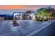Home exterior with a three-car garage, desert landscaping, and brick paver driveway at 7300 Fresh Harvest Ave, Las Vegas, NV 89131