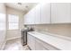 Laundry room features sink, white cabinets, tile floors, and stainless steel appliances at 7332 Redhead Dr, North Las Vegas, NV 89084