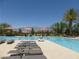 Inviting pool area with comfortable lounge chairs, umbrellas, and scenic mountain views at 7332 Redhead Dr, North Las Vegas, NV 89084