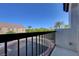 A balcony with black metal railings overlooks street with palm trees and nearby buildings under a clear blue sky at 7505 Emerald Stars St # 101, North Las Vegas, NV 89084