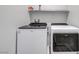 A well-lit laundry room featuring a modern Whirlpool washer and dryer, with a shelf for storage and white painted walls at 7505 Emerald Stars St # 101, North Las Vegas, NV 89084