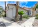 Single-story home showcasing desert landscaping, lush palm trees and a white two-car garage and tile roof at 7865 March Brown Ave, Las Vegas, NV 89149