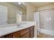 Well-lit bathroom with a wood vanity, white countertops, a large mirror, and a shower-tub combination at 8448 Cambria Cellars Ct, Las Vegas, NV 89139