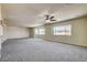 Expansive living room with neutral carpeting, ceiling fan, and multiple windows, offers a versatile and comfortable living area at 8448 Cambria Cellars Ct, Las Vegas, NV 89139