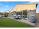 A well manicured backyard with lush synthetic grass, patio, and outdoor seating offers comfortable outdoor space at 8705 Fordster St, Las Vegas, NV 89166