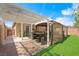 This backyard features an outdoor dining set under a pergola and a gazebo on a brick patio next to the artificial lawn at 9104 Ashiwi Ave, Las Vegas, NV 89178