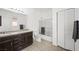 Bright bathroom featuring double sinks, tiled floors, shower over tub, and closet at 9104 Ashiwi Ave, Las Vegas, NV 89178