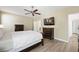 Spacious main bedroom featuring wood-look floors, ceiling fan, and an entertainment center with TV at 9104 Ashiwi Ave, Las Vegas, NV 89178