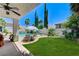 Spacious backyard featuring green grass, pool, spa, lounge chairs, and covered patio at 10249 Wisteria Hills Ct, Las Vegas, NV 89135
