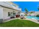 Spacious backyard featuring green grass, pool, spa, lounge chairs, and covered patio with ceiling fan at 10249 Wisteria Hills Ct, Las Vegas, NV 89135
