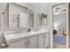 Bright bathroom featuring dual sinks, quartz countertop, framed mirrors, and open doorway to bedroom at 10249 Wisteria Hills Ct, Las Vegas, NV 89135