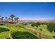 Picturesque backyard view of a golf course, lake, mountains, and palm trees from a lush, green lawn at 12 Strada Di Circolo, Henderson, NV 89011