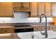 Close-up of a kitchen sink with stainless steel faucet and gas cooktop in background at 12 Strada Di Circolo, Henderson, NV 89011