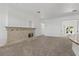 Open living room with fireplace, neutral carpet, and kitchen access at 12 Strada Di Circolo, Henderson, NV 89011