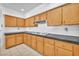 Efficient kitchen features wood cabinetry, tile floors, a white backsplash, and black countertops at 1951 Moyer Dr, Henderson, NV 89074