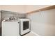 Bright laundry room with modern washer and dryer, plus overhead shelving for convenient storage solutions at 208 Coltrane Canyon Ave, Henderson, NV 89011