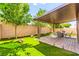 Beautiful backyard with a covered patio, artificial grass, and mature trees providing shade and privacy at 2333 Mundare Dr, Henderson, NV 89002