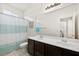 Well-lit bathroom with a double sink vanity, white tile floors and a shower with blue striped curtain at 33 Via Di Mello, Henderson, NV 89011