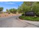 A 'Lake Las Vegas Sports Club' sign is framed by lush greenery and a paved road at 33 Via Di Mello, Henderson, NV 89011