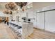 Open-concept kitchen with marble waterfall island, stainless appliances, and a grand, decorative chandelier at 4162 Matterhorn Way, Las Vegas, NV 89124