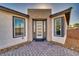 Modern front door with sidelights and a brick paver walkway, flanked by windows and manicured landscaping at 5091 E Beacon Ridge Dr, Pahrump, NV 89061
