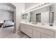 Bright bathroom featuring a double vanity, large mirrors, and an open doorway to a bedroom at 517 Casa Del Norte Dr, North Las Vegas, NV 89031