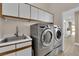 Practical laundry area featuring a utility sink, modern machines, and white cabinets for organization at 5205 Coral Glow Ct, Las Vegas, NV 89149