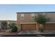 A townhouse with an attached two-car garage with a well-maintained driveway and green landscape at 5209 Silica Chalk Ave, Las Vegas, NV 89115