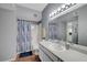 Bright bathroom with white cabinets, mirror, and shower with patterned curtain at 6650 W Warm Springs Rd # 1083, Las Vegas, NV 89118