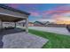 A backyard view with a covered patio, artificial turf, and beautiful sunset in the background at 7258 W Le Baron Ave, Las Vegas, NV 89178