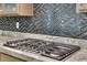 Close-up of a gas cooktop with granite countertops and a mosaic tile backsplash at 7258 W Le Baron Ave, Las Vegas, NV 89178