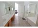 Bright bathroom featuring a double vanity with tile floors and a glass-enclosed shower and soaking tub at 7325 Perkins Hill St, Las Vegas, NV 89166