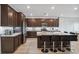 Spacious kitchen features dark wood cabinets, granite countertops, stainless steel appliances, and a large island with seating at 7616 Quail Dust St, North Las Vegas, NV 89084