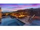 Inviting backyard with a pool, hot tub, fire feature, chairs, and city views at dusk at 778 Horizon Canyon Dr, Henderson, NV 89052