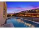 A twilight pool with water feature and a serene backdrop of landscaping and a hillside to create a luxurious and peaceful retreat at 778 Horizon Canyon Dr, Henderson, NV 89052