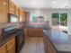 Well-equipped kitchen featuring wood cabinets, granite countertops, stainless steel appliances, and sliding glass door to the backyard at 8253 Pearl Oasis Ct, Las Vegas, NV 89139